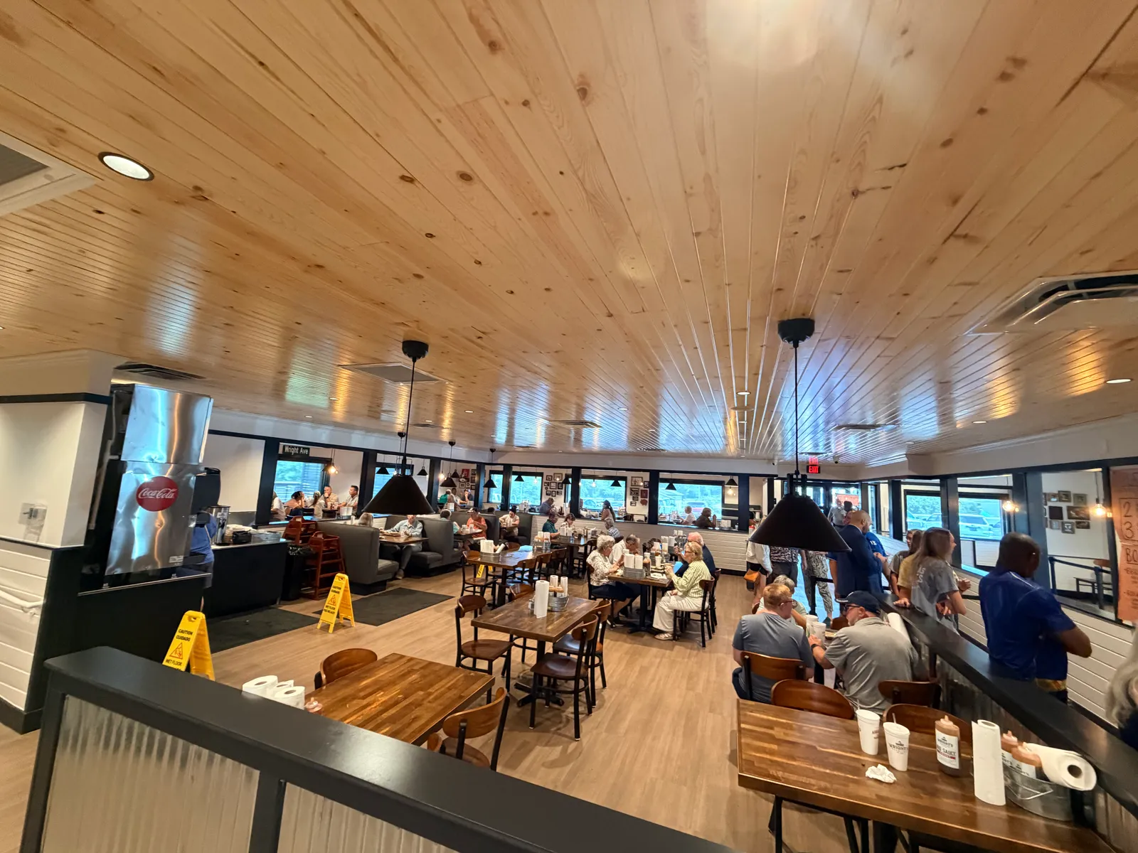 The bright, modern dining room at Wright's Barbecue in Benton — pine plank ceiling, wood tables, booths, and a full lunch crowd