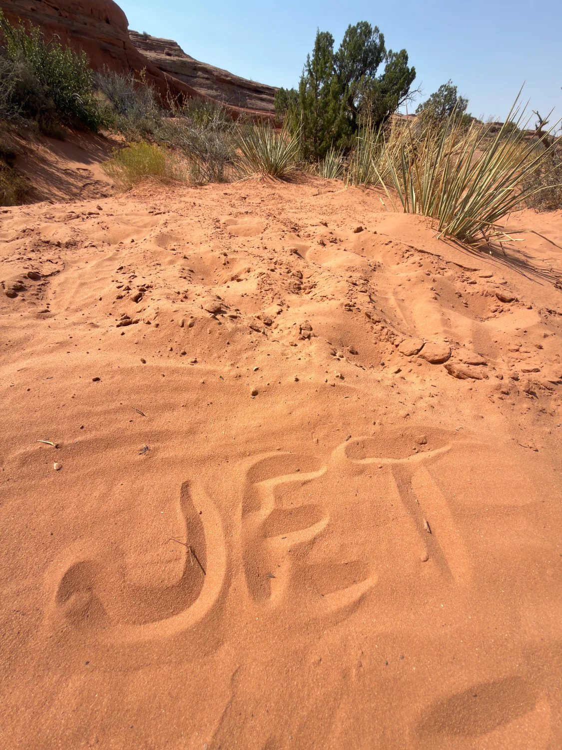 The word JET written by hand in the red sand of the Moab desert
