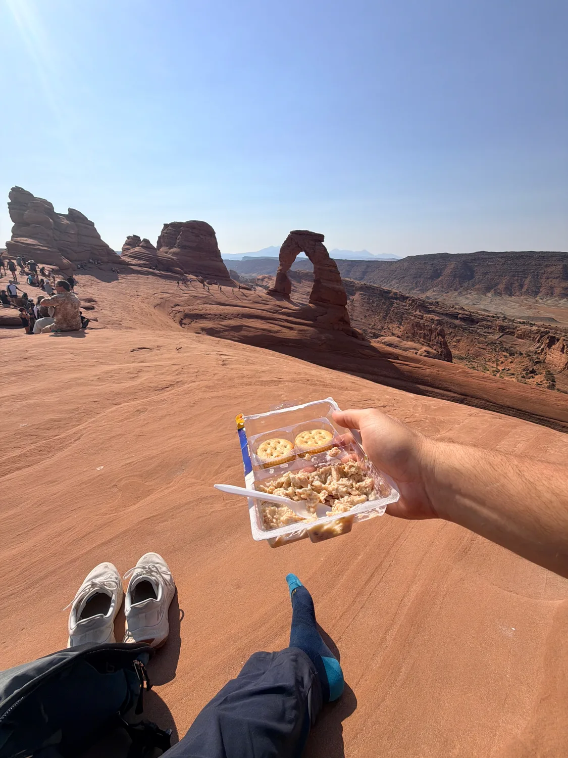 Crackers and tuna salad held up with Delicate Arch and red rock in the background