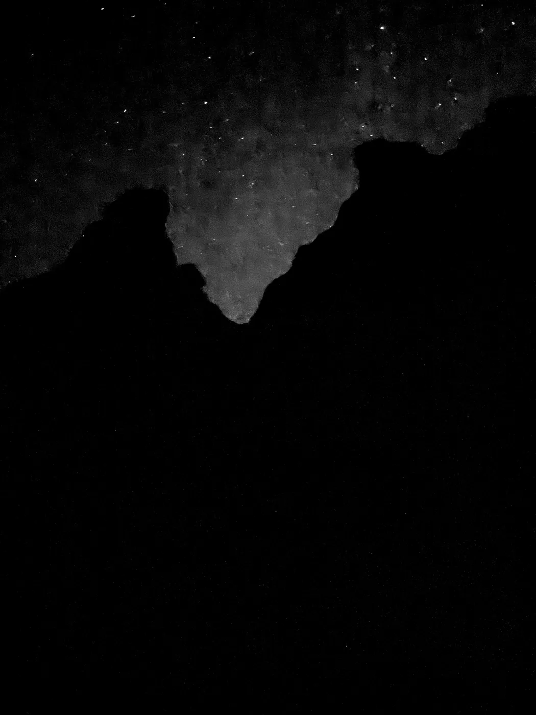 A grainy real photograph of the night sky over Moab, mostly black rock with a notch of stars