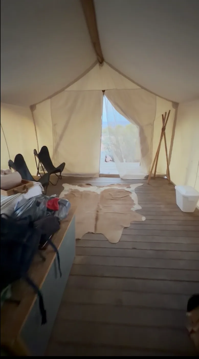 Interior of a canvas safari tent at Under Canvas Moab with a cowhide rug and the flap open to the desert
